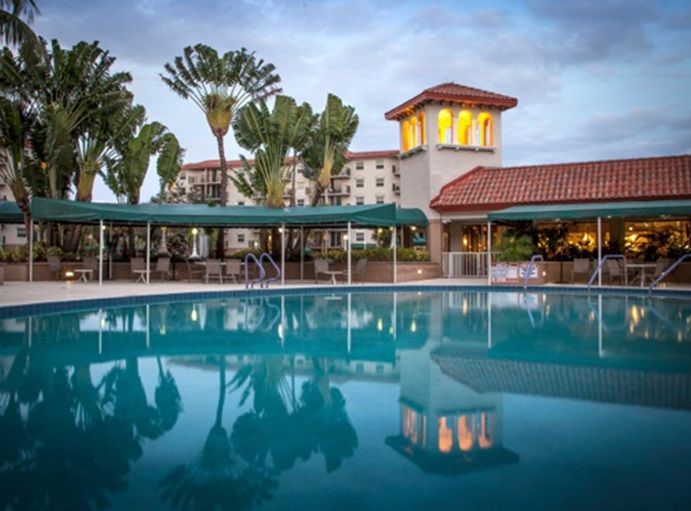 A serene outdoor swimming pool at a hotel resort surrounded by palm trees.