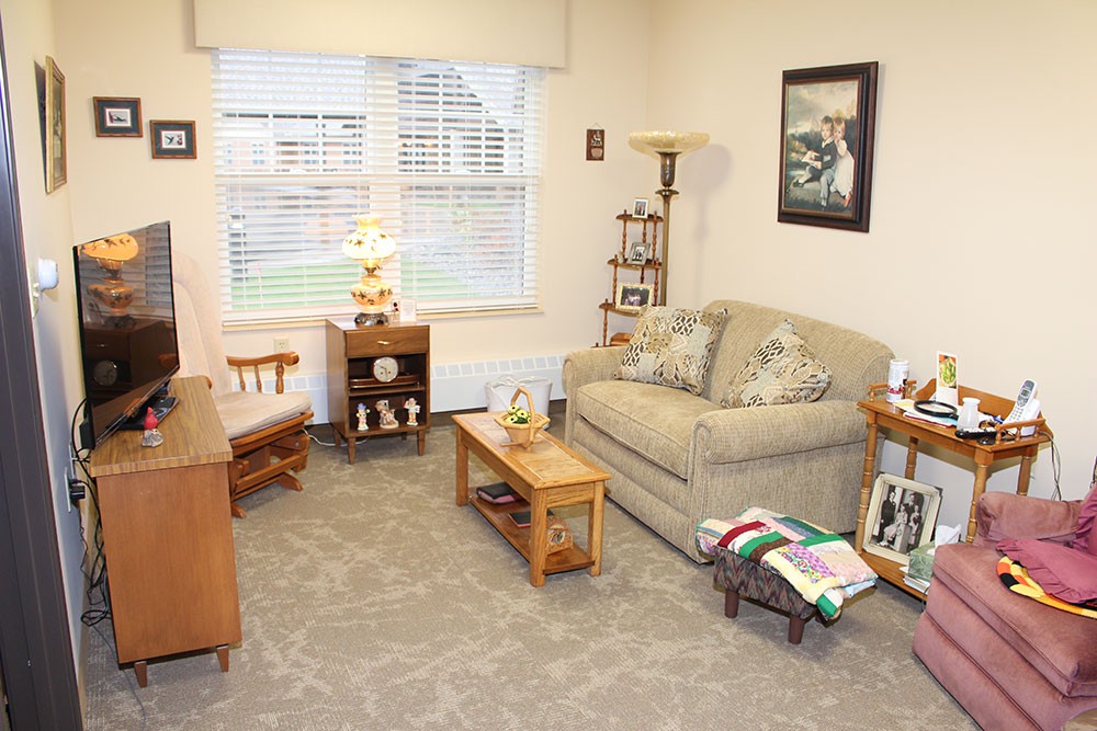 A cozy living room with a sofa, armchair, and coffee table, decorated with various items.
