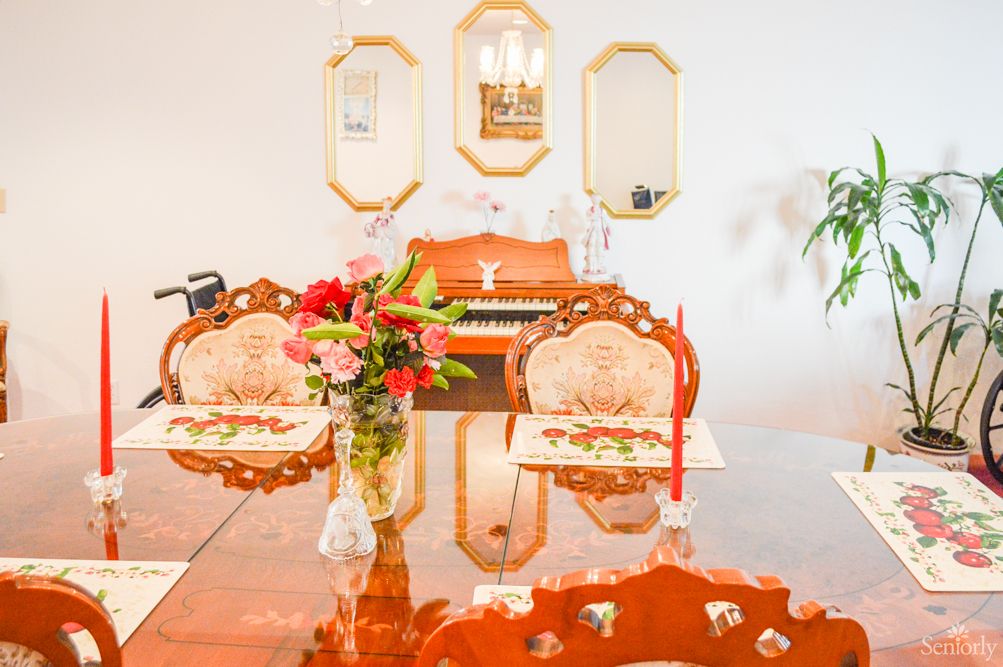 A beautifully arranged dining room with ornate chairs, a floral centerpiece, and mirrors reflecting the warm decor.