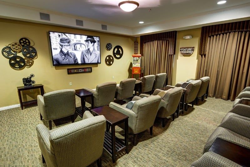 A cozy home theater setup with rows of comfortable chairs facing a large screen.