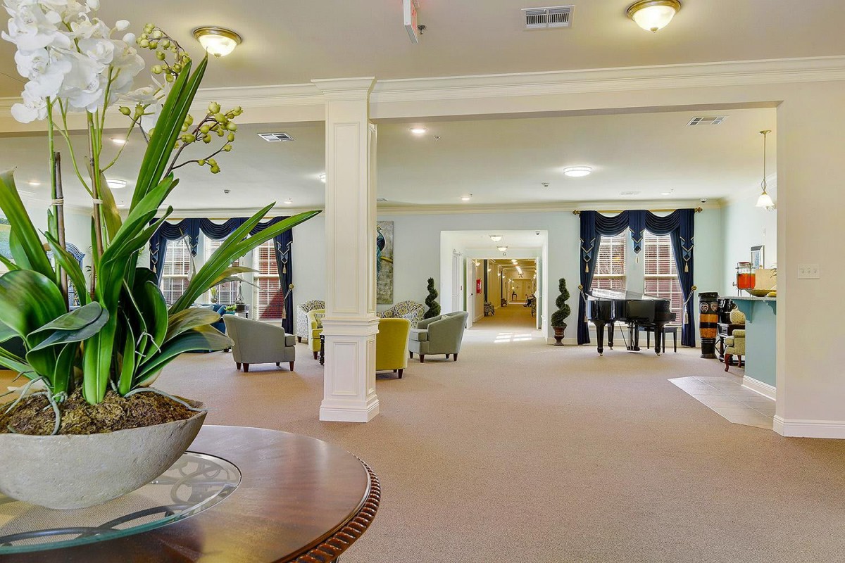 A spacious and elegantly decorated lobby featuring comfortable seating, potted plants, and a grand piano.