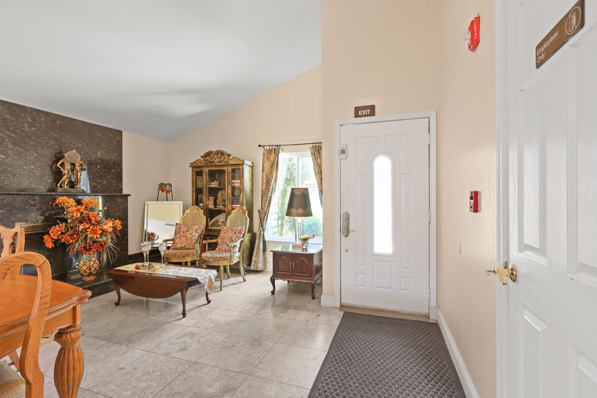 A cozy living room with elegant furniture and decor, featuring armchairs and a cabinet near a doorway.