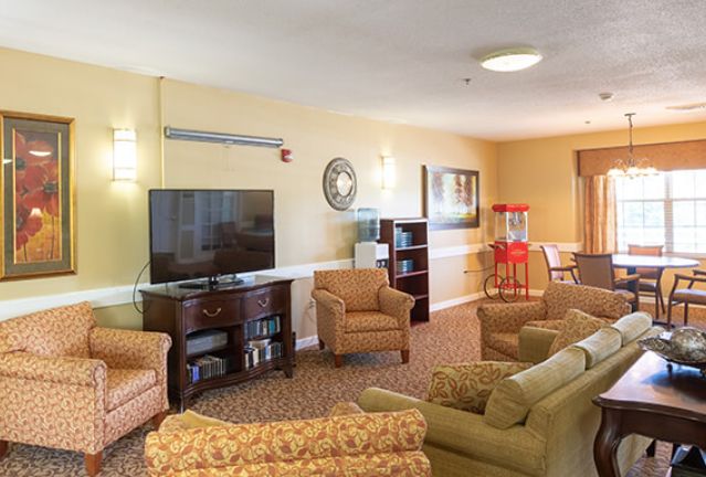 A cozy living room with comfortable seating, a TV, and a popcorn machine.