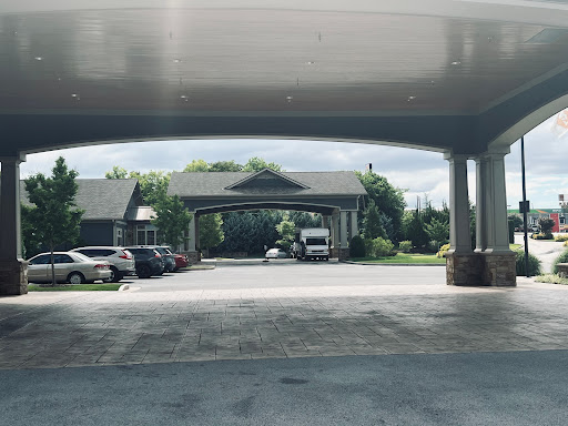 A view of a covered entryway with parked cars and greenery in the background.