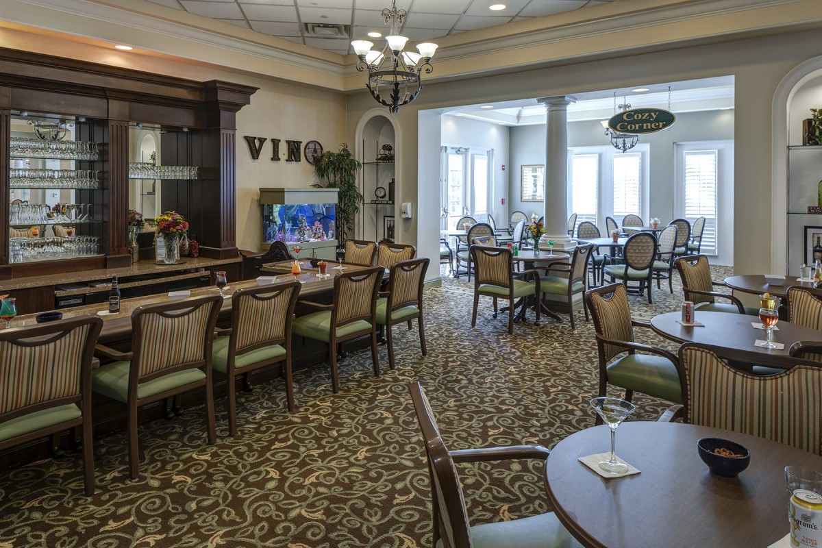 An elegantly designed dining area with multiple tables and chairs, featuring warm lighting and classic decor.