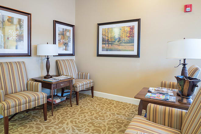 A cozy waiting room with striped chairs, framed artwork, and a decorative carpet.