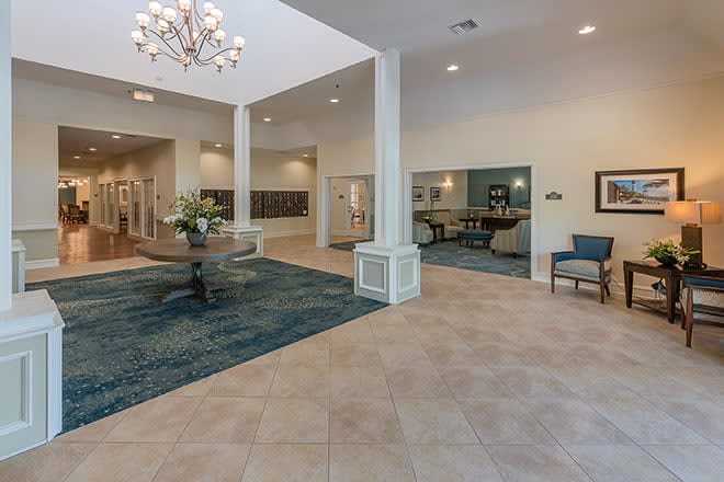 A modern lobby area featuring a chandelier, carpet, and comfortable seating.