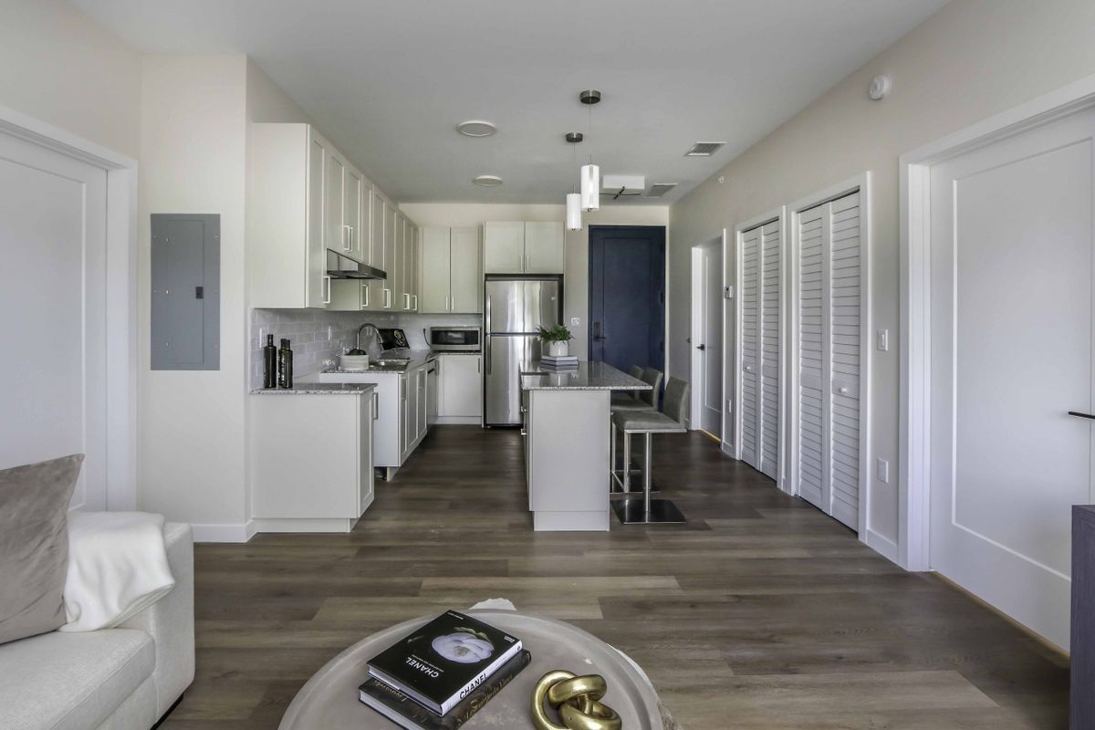 A modern kitchen with an open floor plan, featuring stainless steel appliances and a central island.
