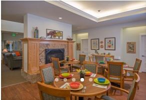 A cozy dining room with tables set for a meal and a decorative fireplace.