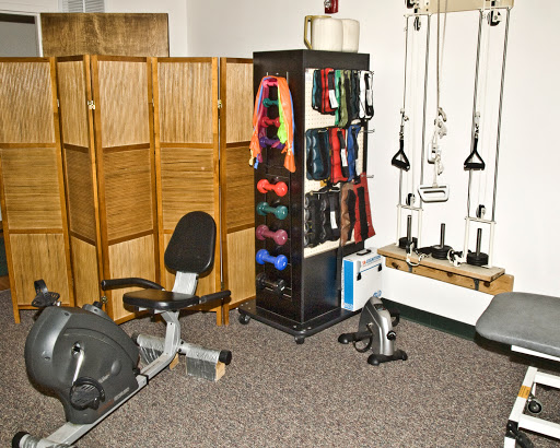 A well-equipped fitness room featuring various exercise equipment, including a rowing machine and a storage rack filled with colorful resistance bands.