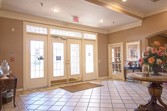 A bright lobby with tiled flooring and large glass doors leading outside.