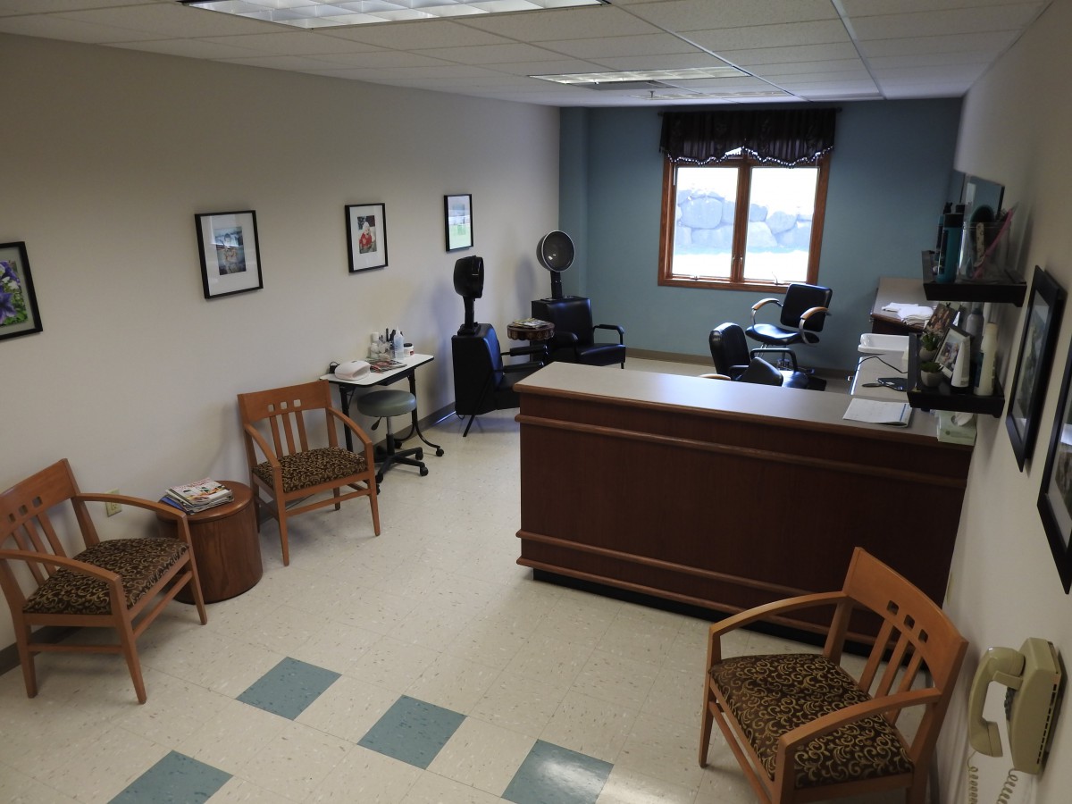 A small office waiting room with chairs, a reception desk, and a window.