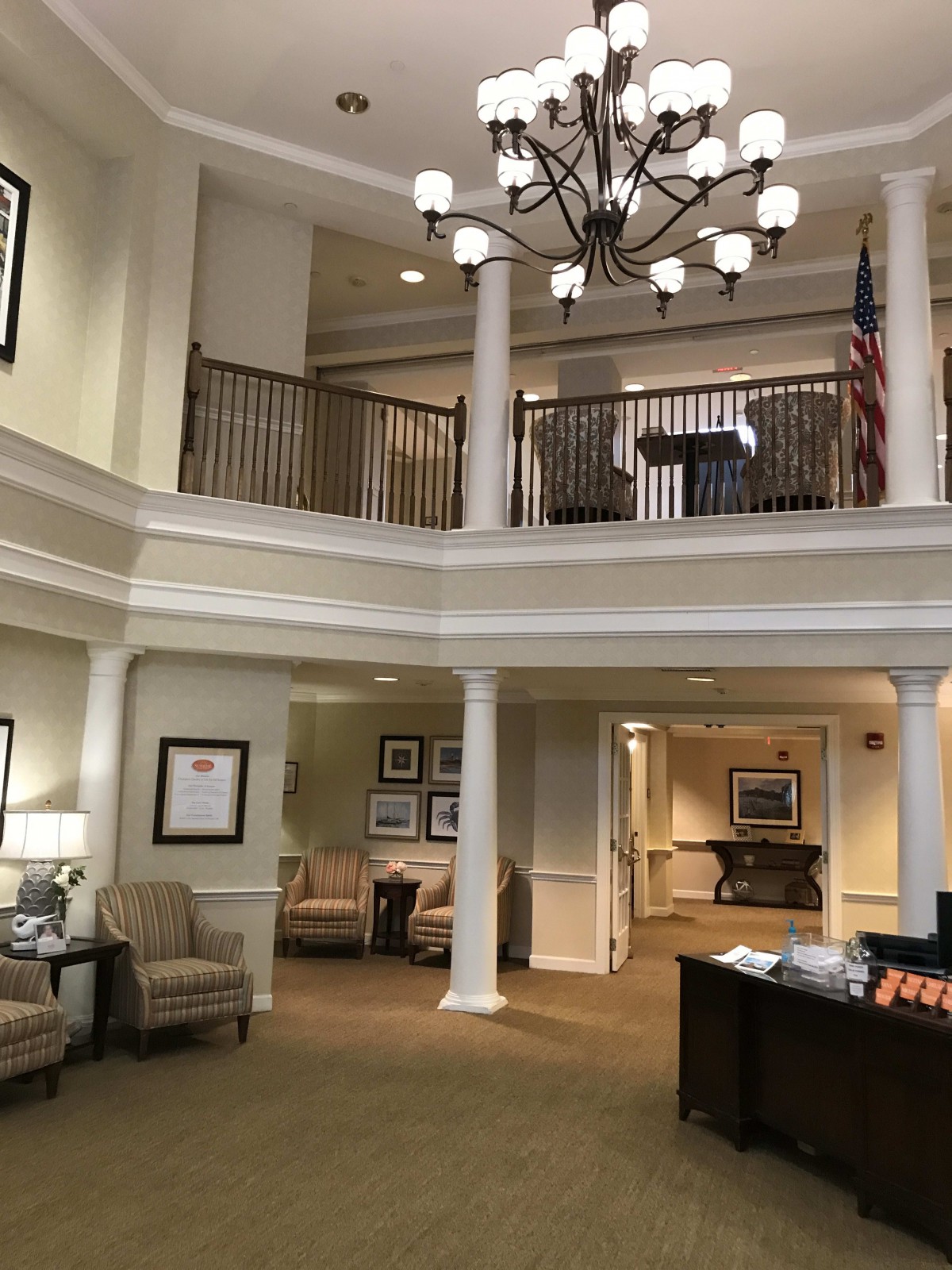 A spacious lobby area featuring a chandelier, seating, and a reception desk.