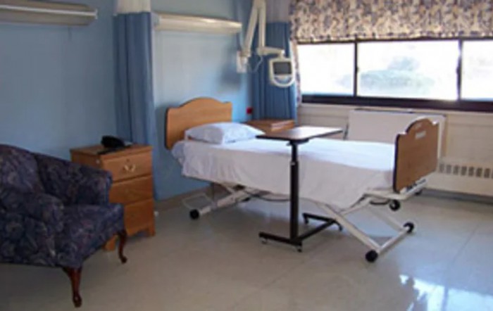 An empty hospital room with a bed and medical equipment.