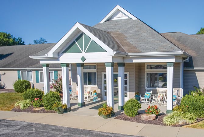 A modern building entrance with columns and landscaped surroundings.