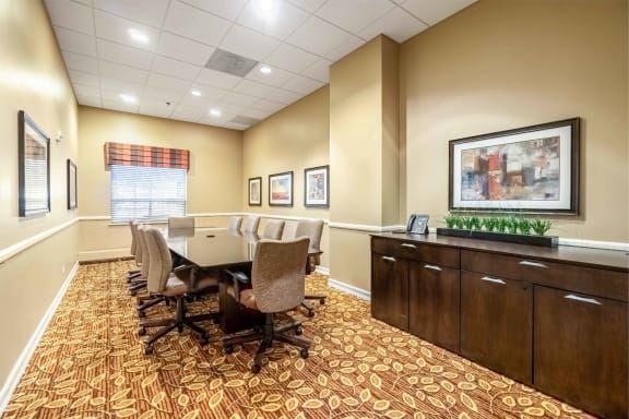 A well-equipped conference room with a long table surrounded by chairs, featuring modern decor and artwork on the walls.