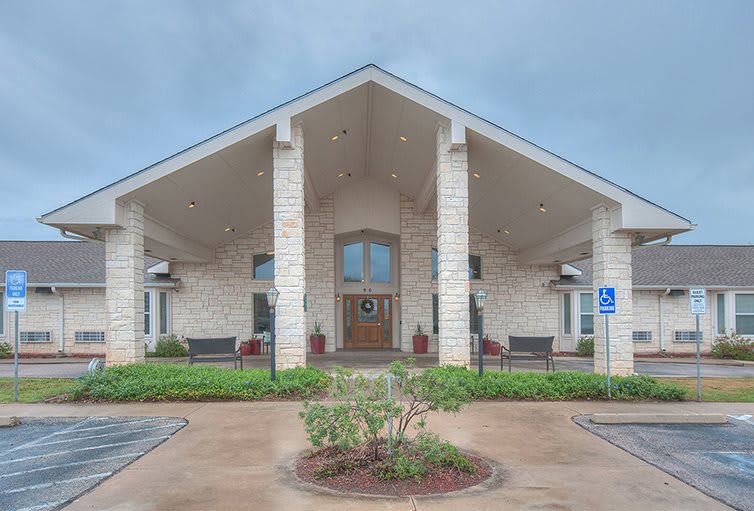 A symmetrical building entrance with columns, surrounded by landscaping under an overcast sky.