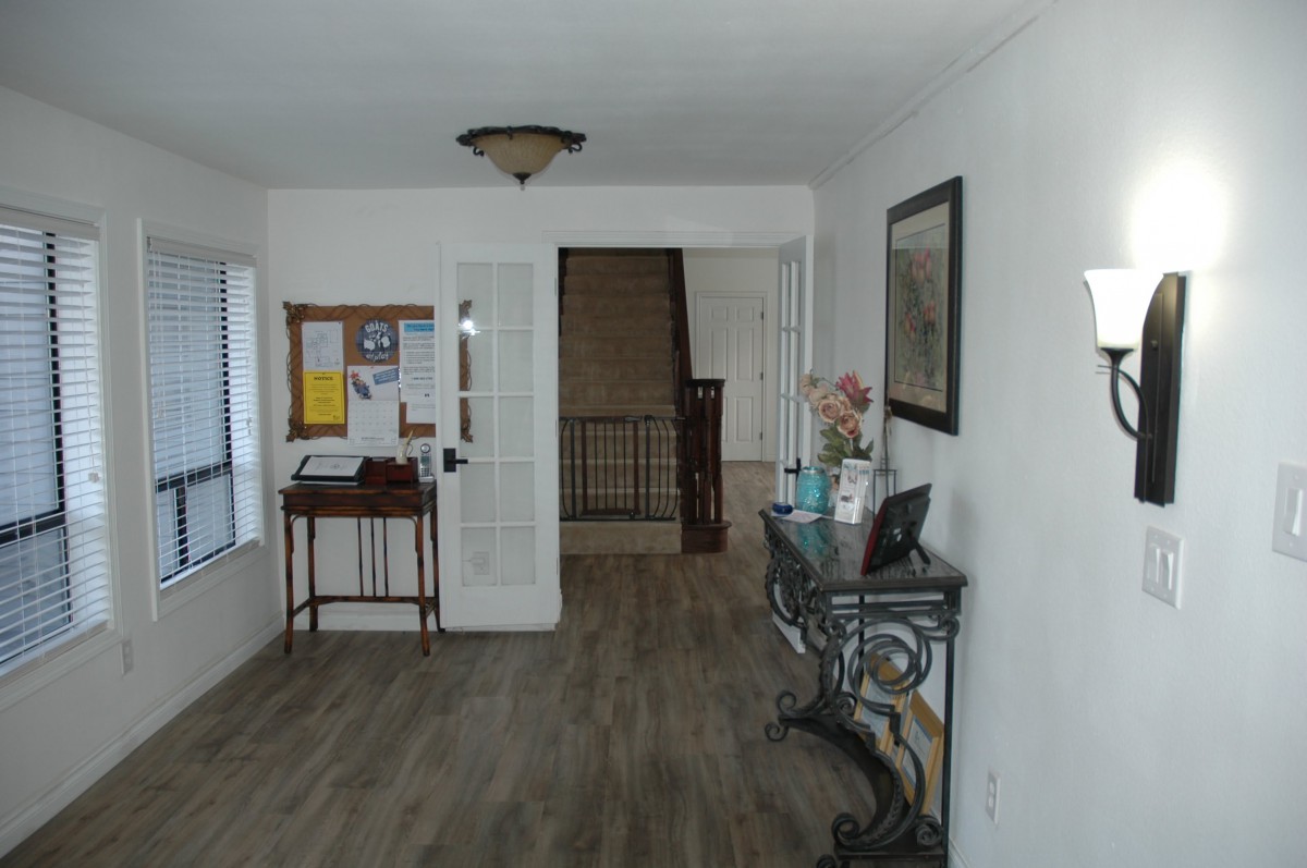 A welcoming foyer with a staircase, decorated with a table, mirror, and a bulletin board.