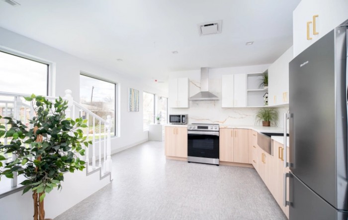 A bright and modern kitchen with minimalist design, featuring white cabinets and wood accents.