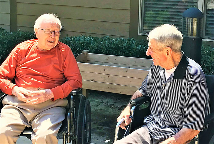 Two elderly men enjoying a conversation outdoors.
