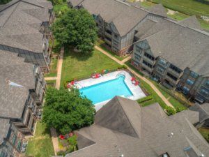 Aerial view of an apartment complex featuring a central swimming pool.