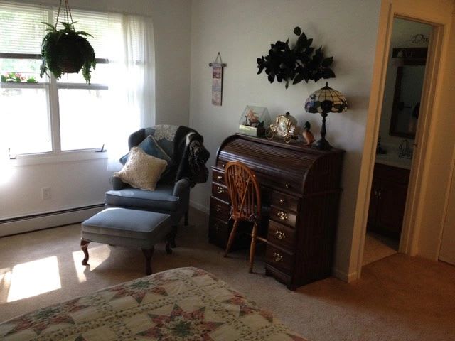 A cozy living room corner featuring a vintage roll-top desk and a comfortable armchair by the window.