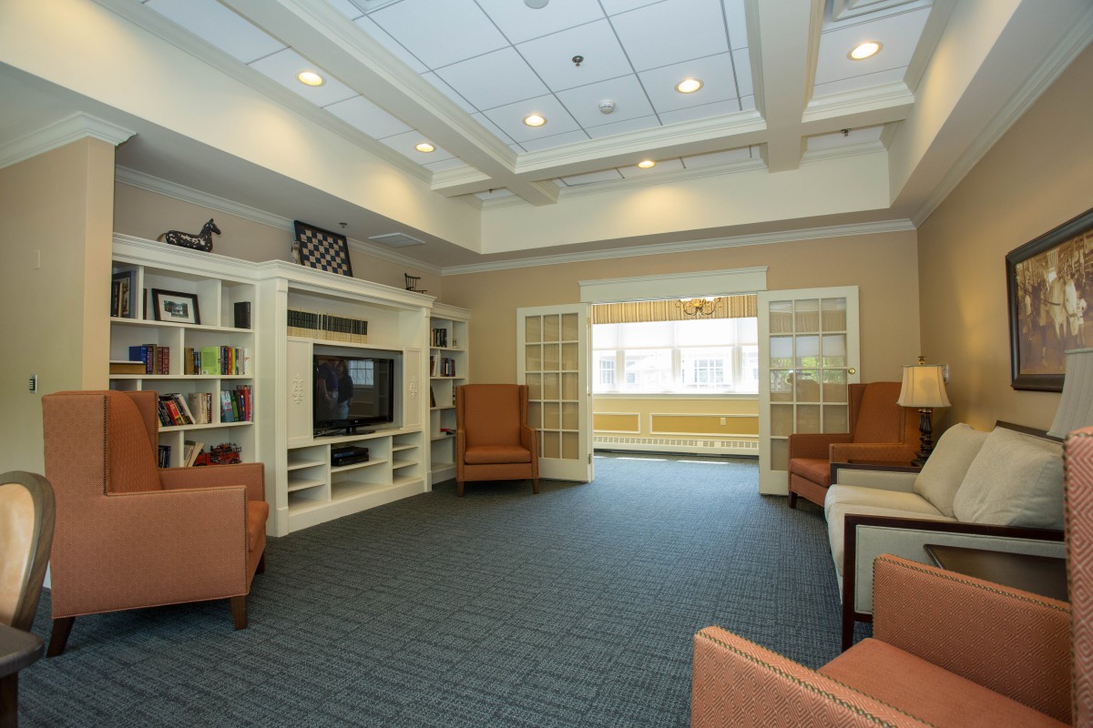 A cozy living room with a television, bookshelves, and comfortable seating.