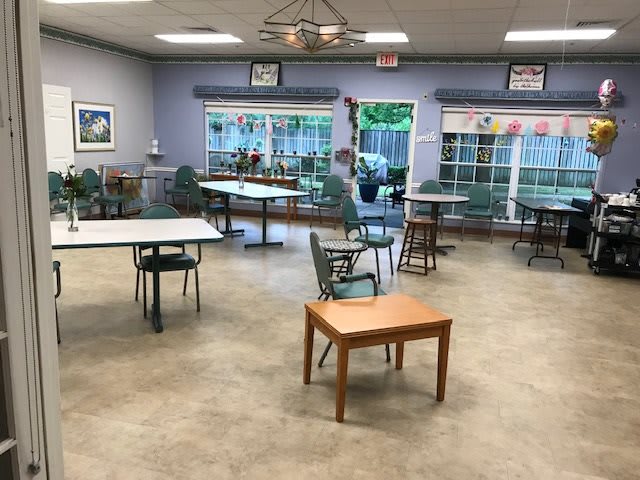 A spacious indoor community center room with tables and chairs arranged for a gathering.