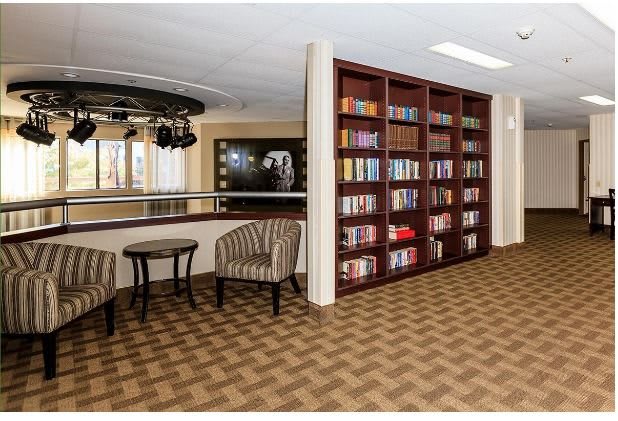 A cozy library corner with bookshelves, comfortable chairs, and a small table.