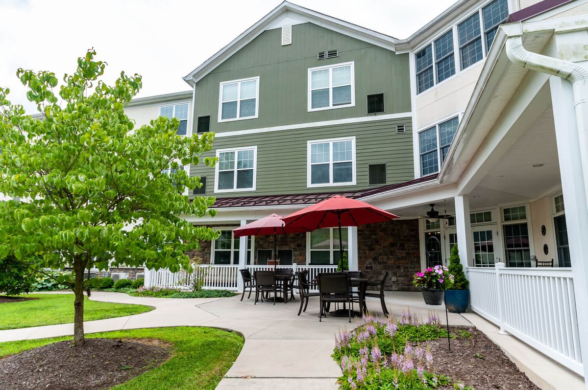 A residential building with a patio area and outdoor seating, surrounded by lush greenery.