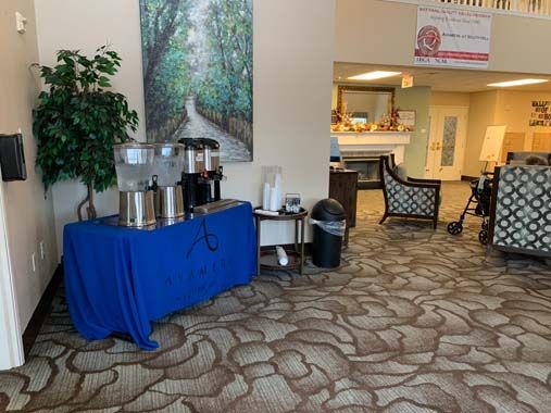A cozy lobby with a coffee and water station, seating area, and decorative wall art.