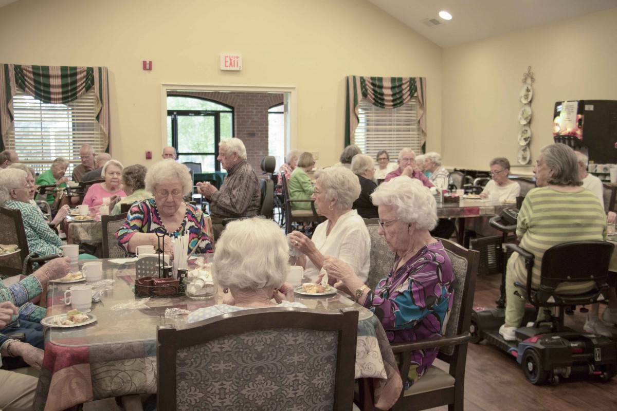 A group of seniors enjoying a meal in a community dining room.