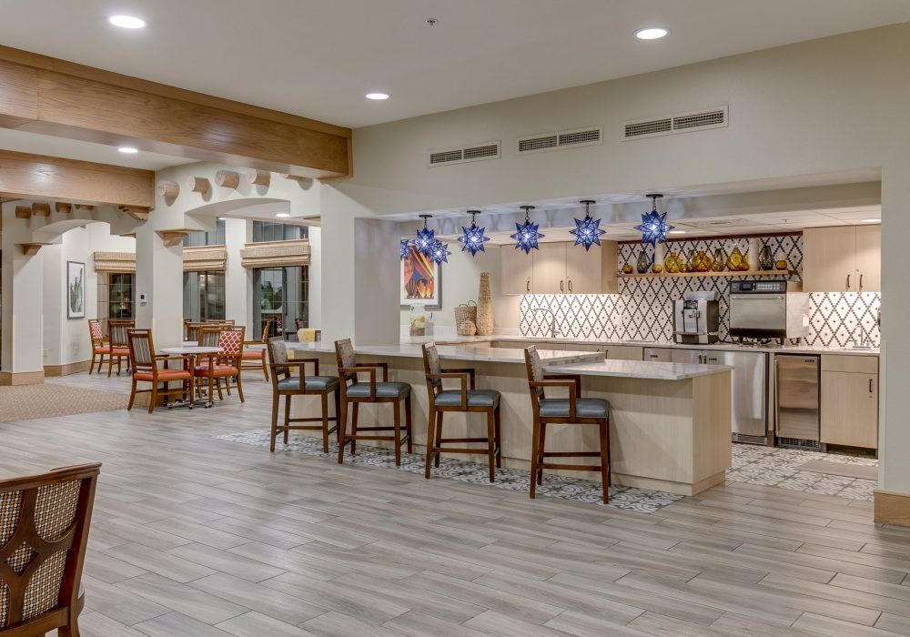 A modern kitchen and dining area with bar stools and stylish lighting.