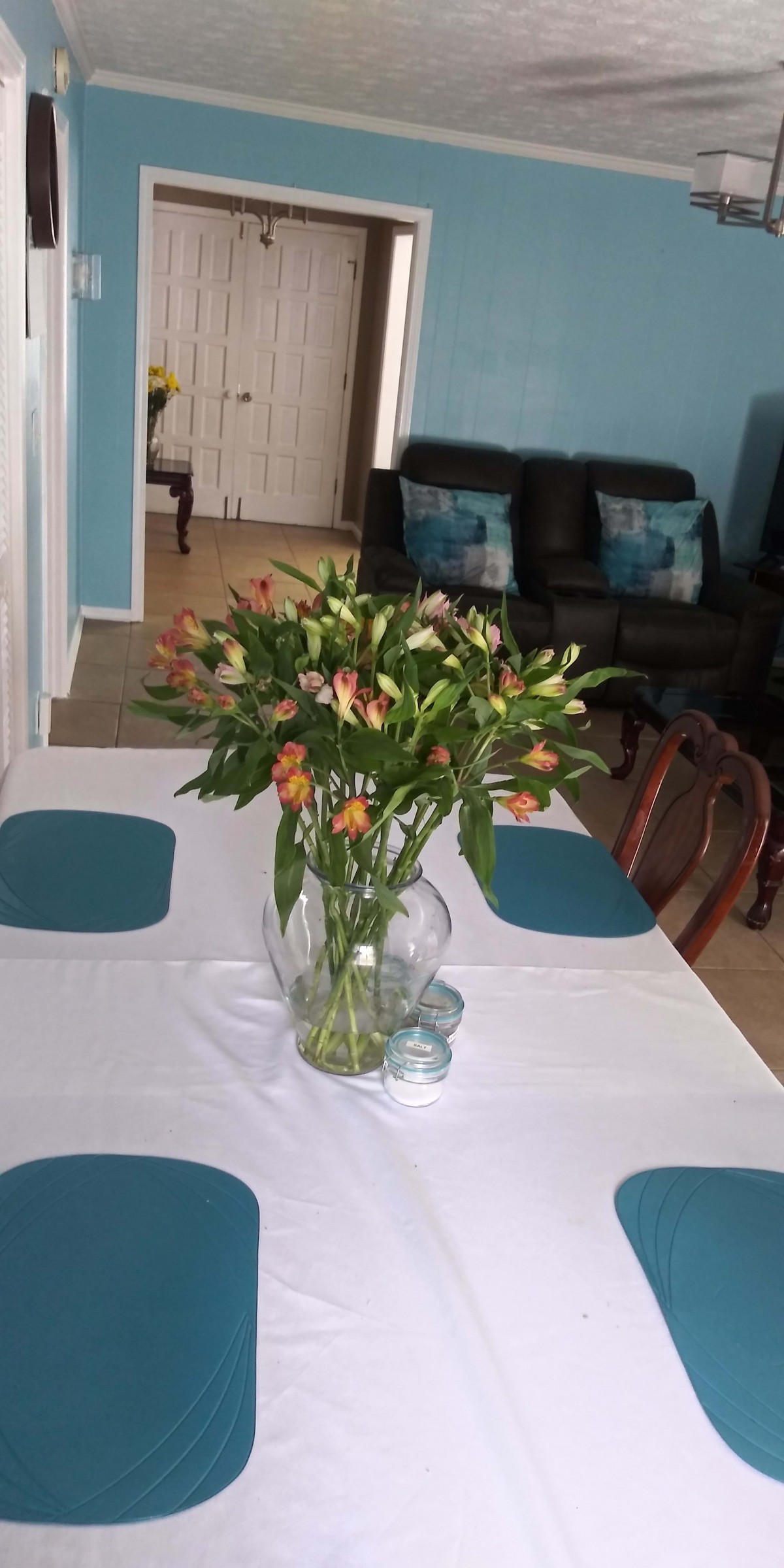 A dining table adorned with a vase of orange lilies as a centerpiece.