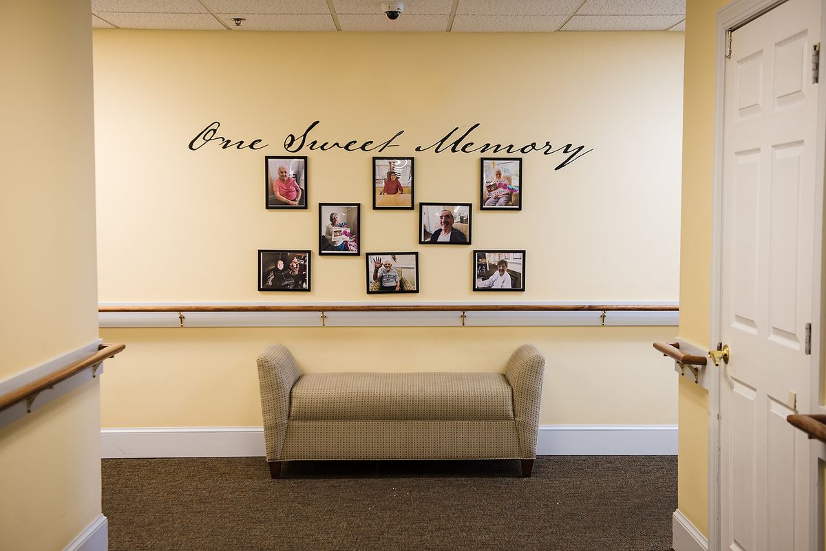 A hallway featuring a 'One Sweet Memory' photo wall with various framed pictures above a cushioned bench.