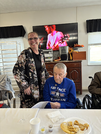 A joyful moment shared between a woman and an elderly veteran in a wheelchair, with music playing in the background.