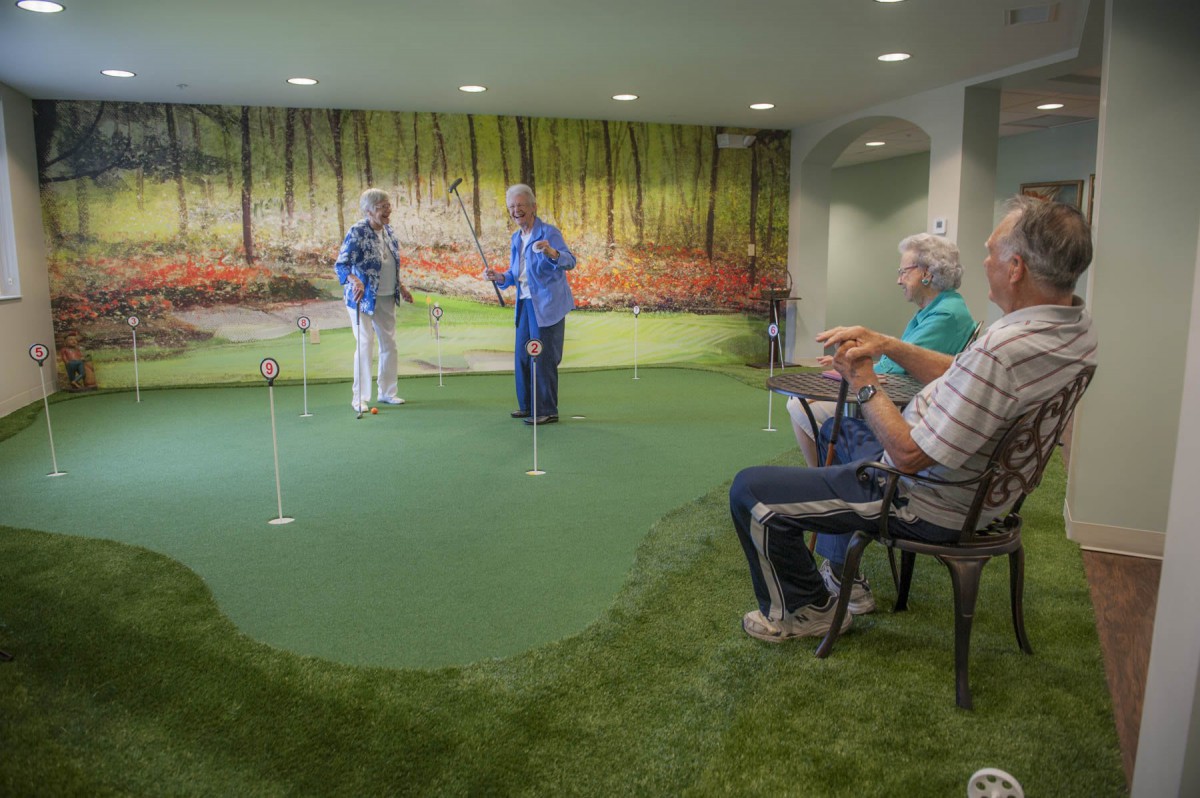 Seniors enjoy a game of mini golf on an indoor putting green.