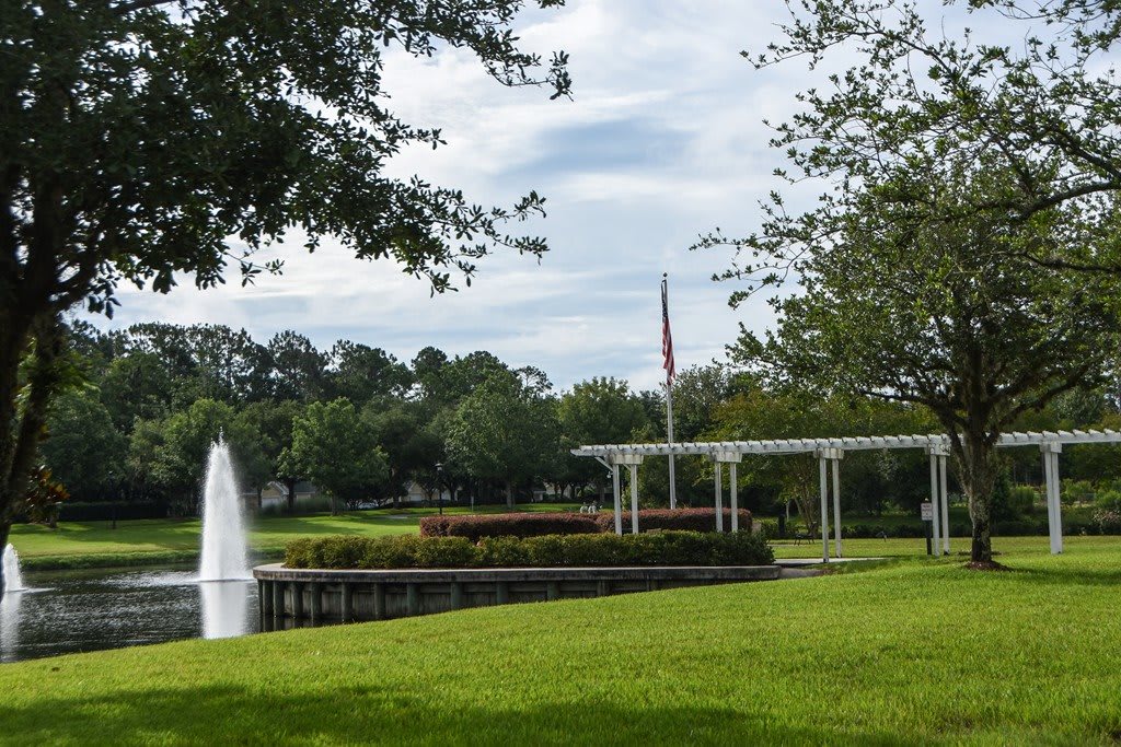 A peaceful park scene with a fountain and lush greenery.