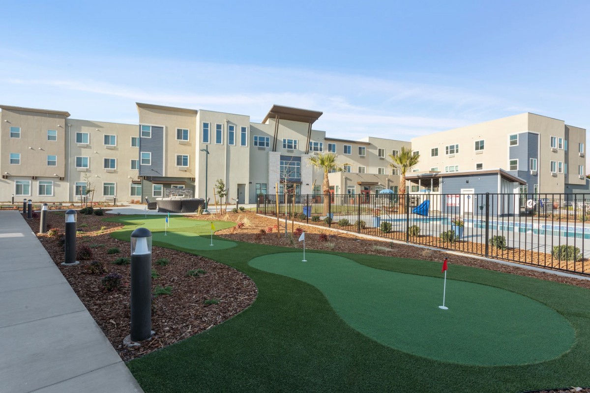 A modern building with a well-maintained putting green in the foreground.