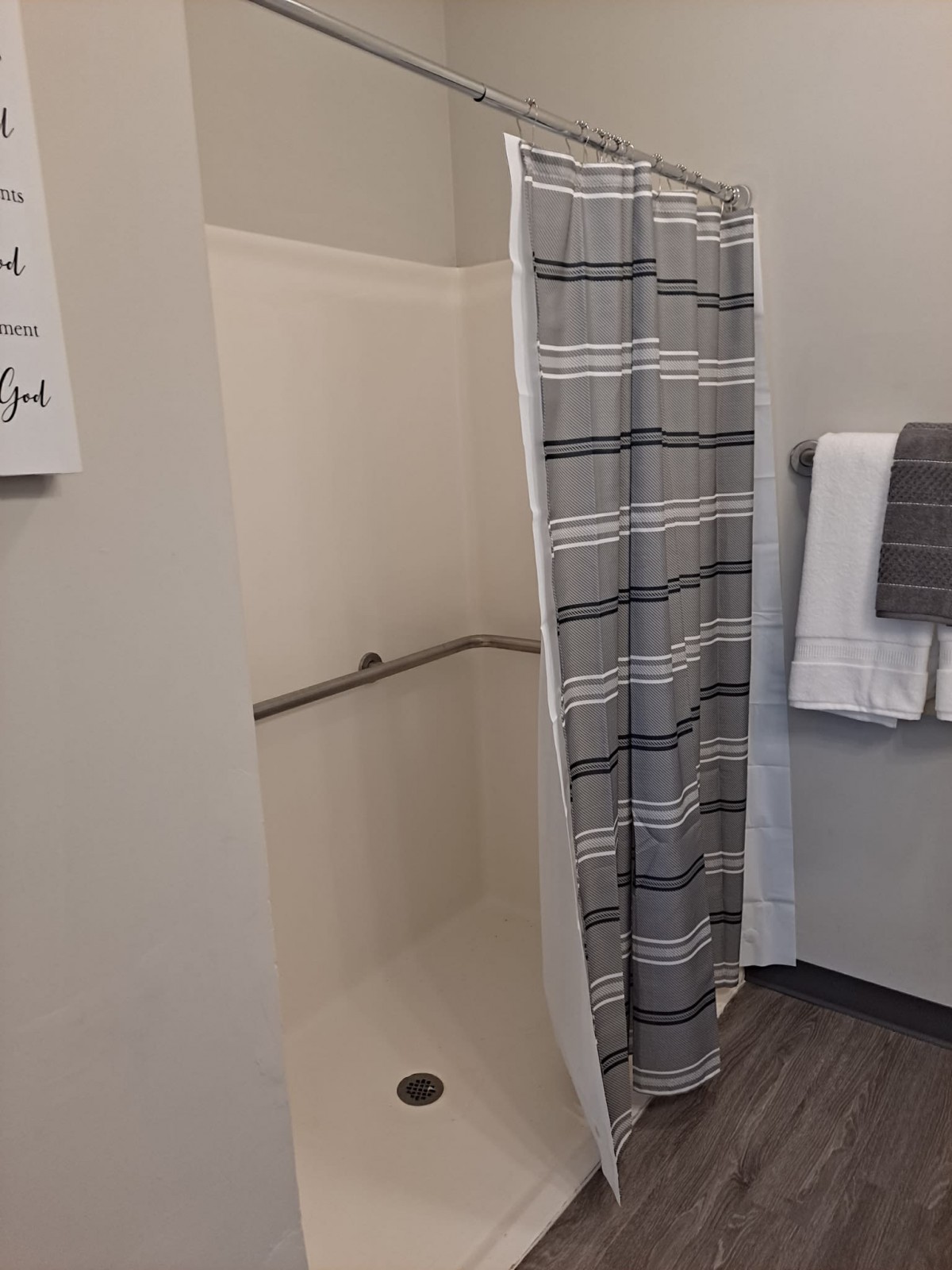 A bathroom featuring a shower with a striped curtain and neatly folded towels on a rack.
