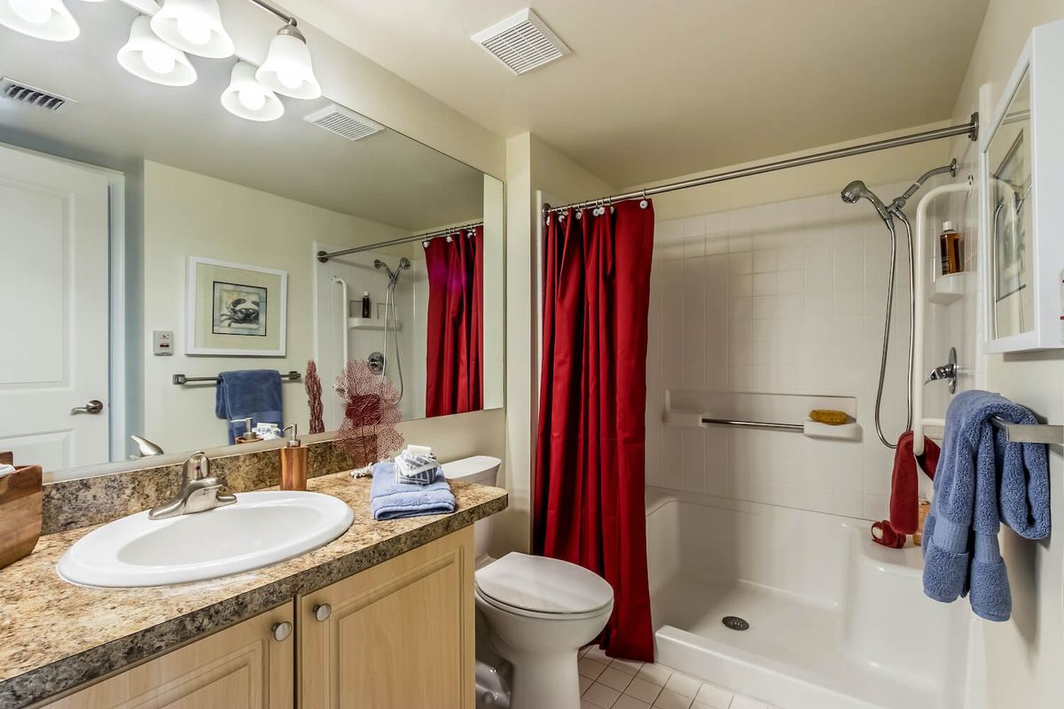 A clean and well-organized bathroom with a red shower curtain.