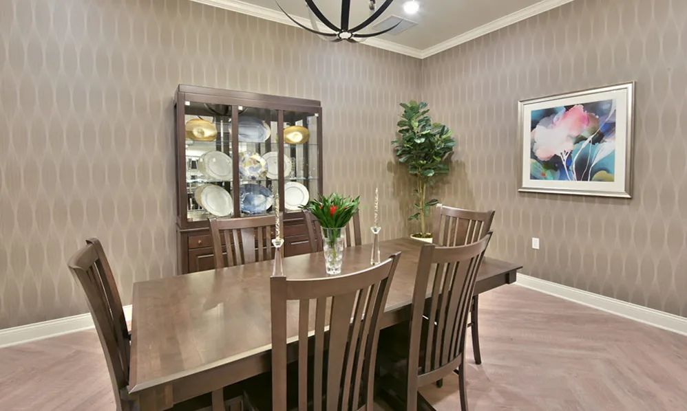 Elegant dining room with a wooden table and chairs, featuring a cabinet with dishes and tasteful decor.