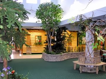 A serene indoor garden featuring a wooden cabin, lush greenery, and inviting seating.