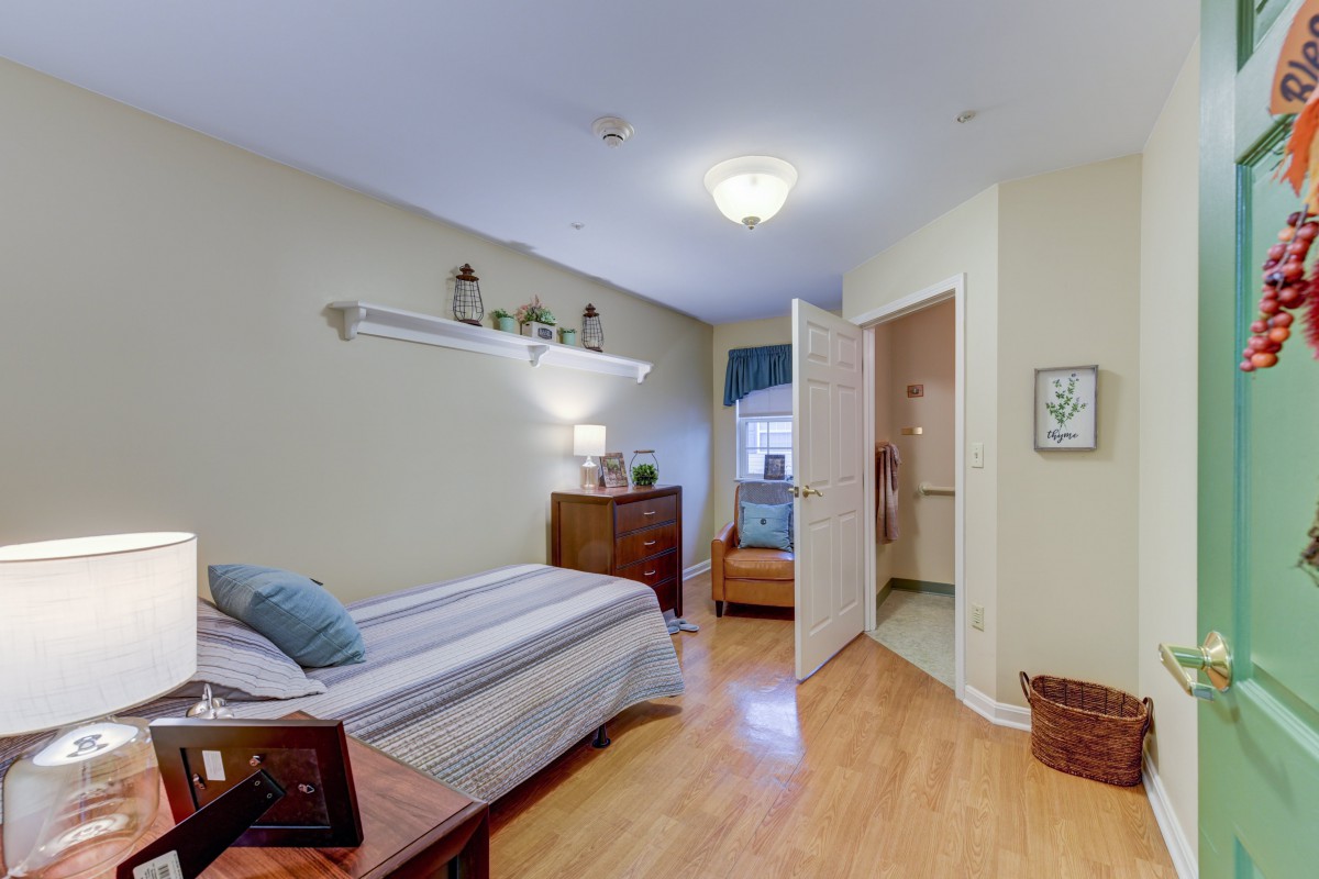 A cozy bedroom with a single bed, wooden floor, and neatly arranged furniture.