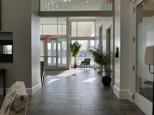 A bright and modern hallway featuring large windows, providing a welcoming atmosphere with indoor plants.