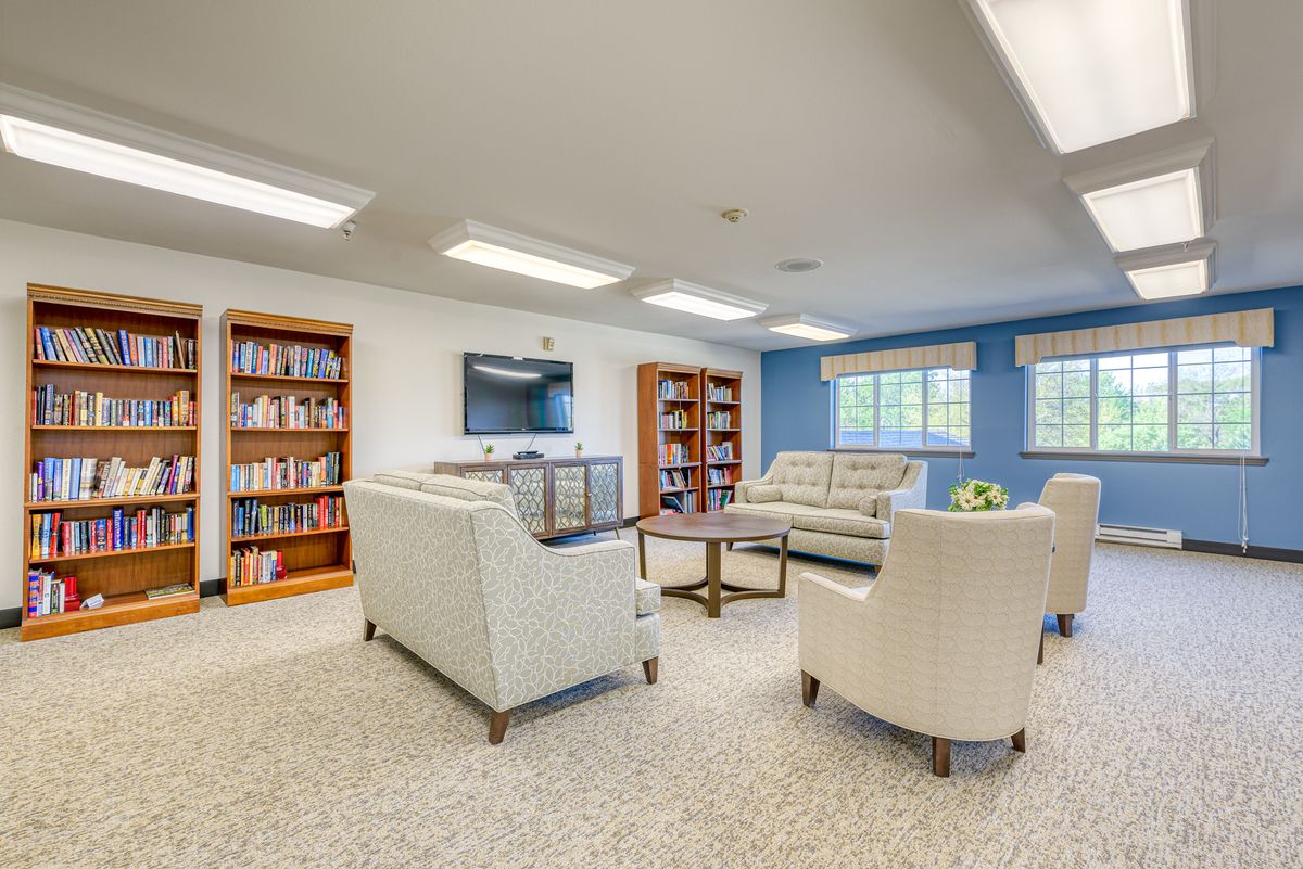 A cozy living room with sofas, chairs, and bookshelves.