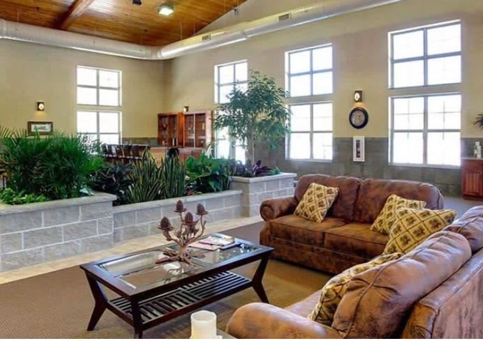 A cozy living room with comfortable sofas, a coffee table, and abundant natural light from large windows.