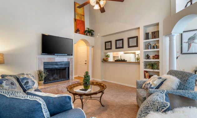 A cozy living room with a fireplace, comfortable seating, and a TV mounted above the mantel.