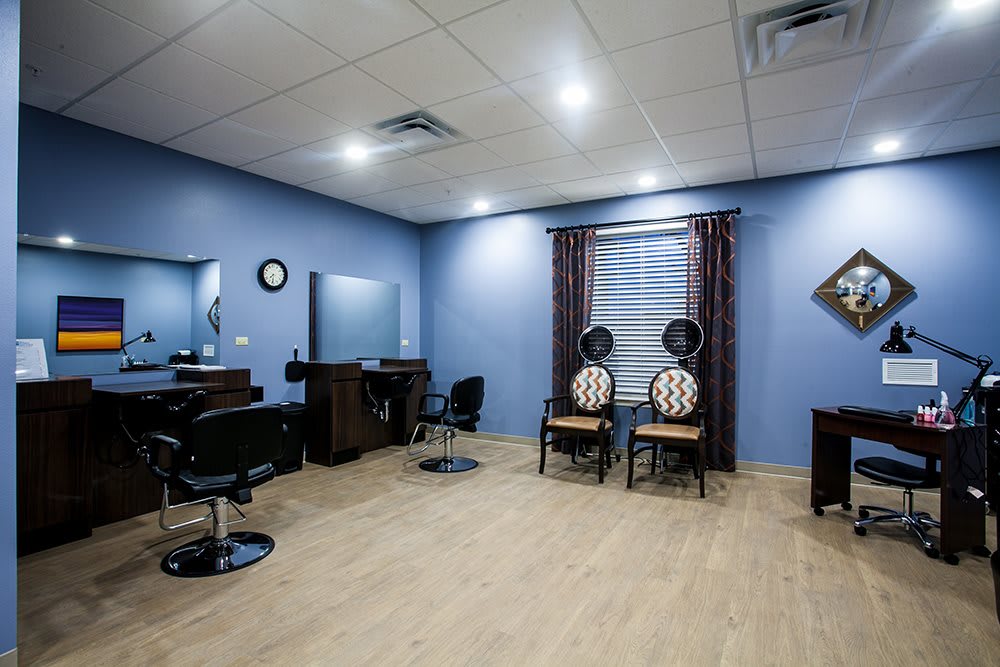 A well-organized salon room with blue walls, featuring chairs and mirrors.