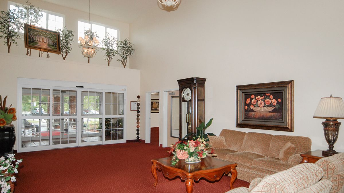 A well-decorated living room with elegant furniture, including a sofa and coffee table, adorned with a chandelier and decorative plants.